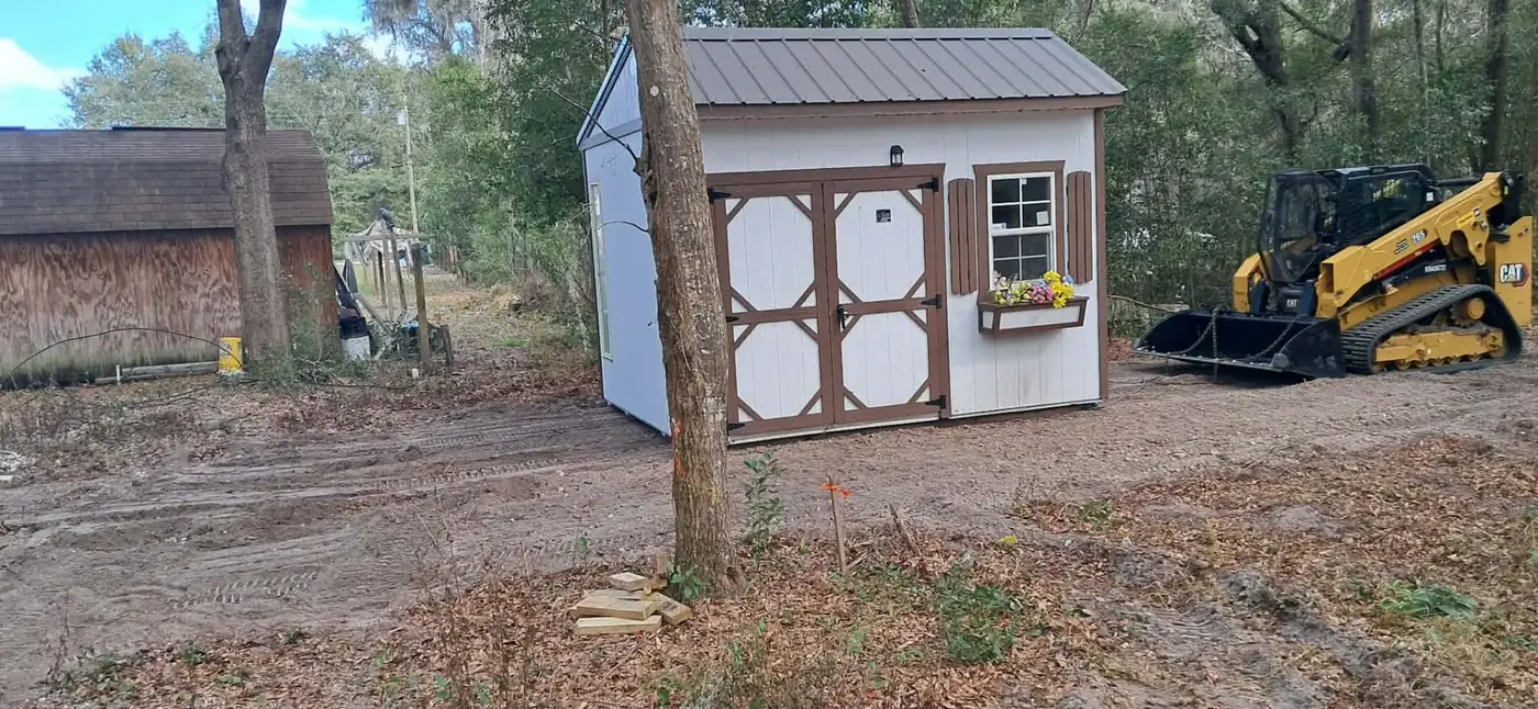 CAT compact track loader beside a repositioned storage shed with open access around the building