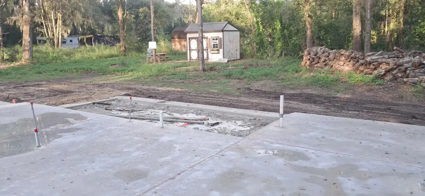 Prepared ground and graded access beside a newly poured concrete foundation