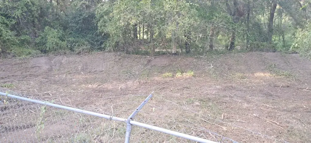 After: graded retention pond banks in Citrus Springs, FL, mulched clean to the tree line behind a chain-link fence